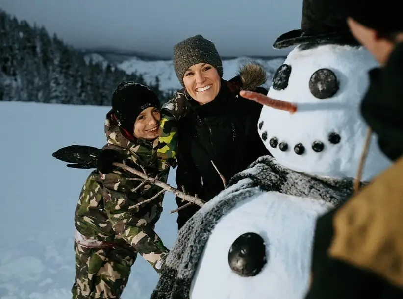 Familia construye un muñeco de nieve por la noche en Mammoth Mountain